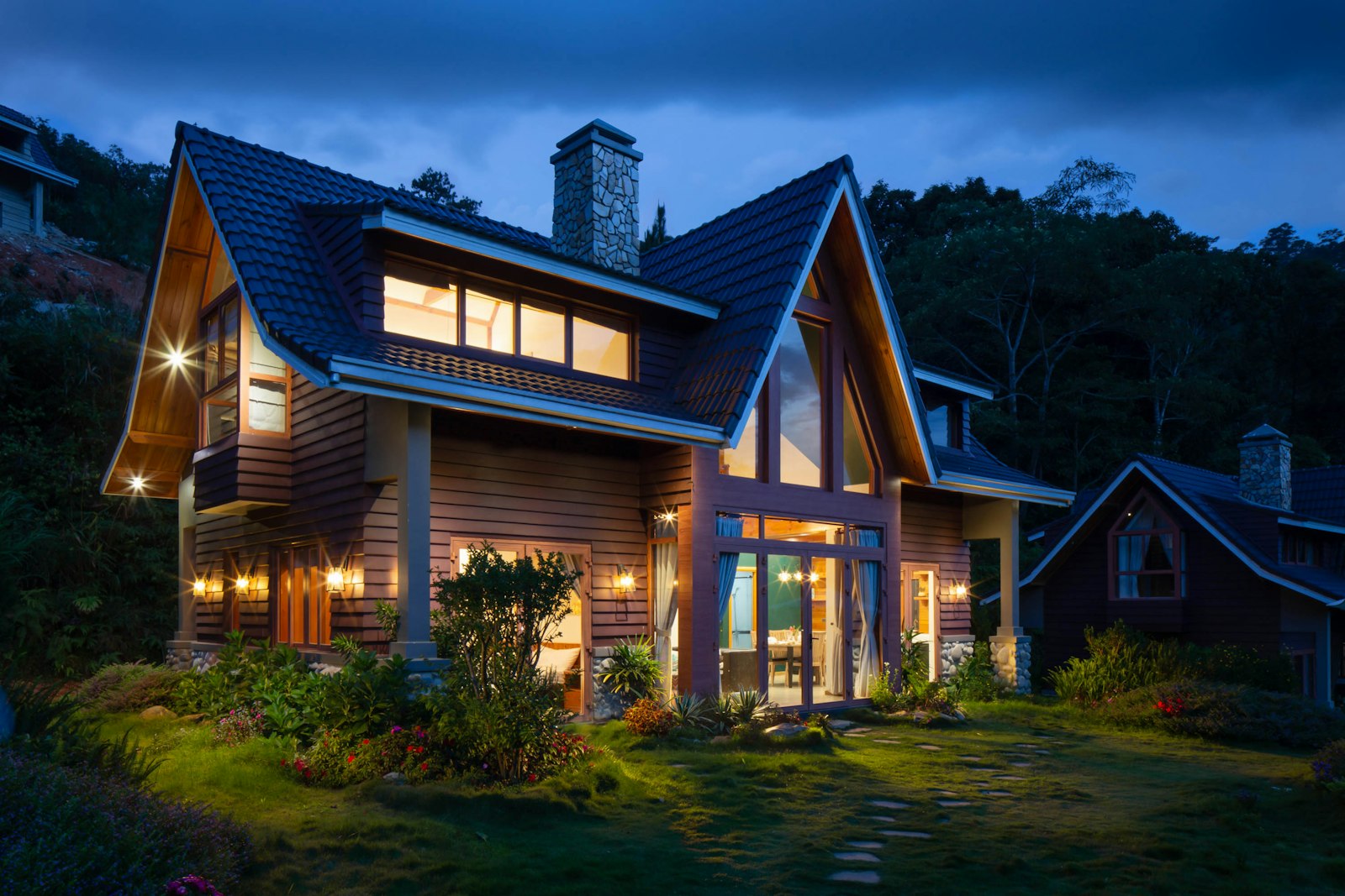 A craftsman-style house at dusk with every window glowing warm against a deep blue Oregon sky